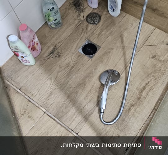 מקלחת עם ראש מקלחת וצינור, בקבוקי סבון על הרצפה